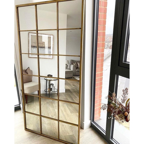 Full length large gold industrial metal window mirror leaning against wall