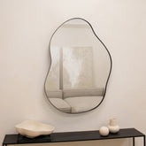 Black metal pond shaped irregular wall mirror displayed vertically on wall