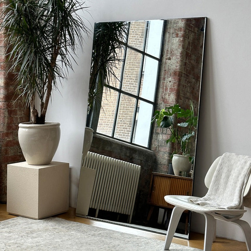Extra large frameless full length rectangular mirror beside chair