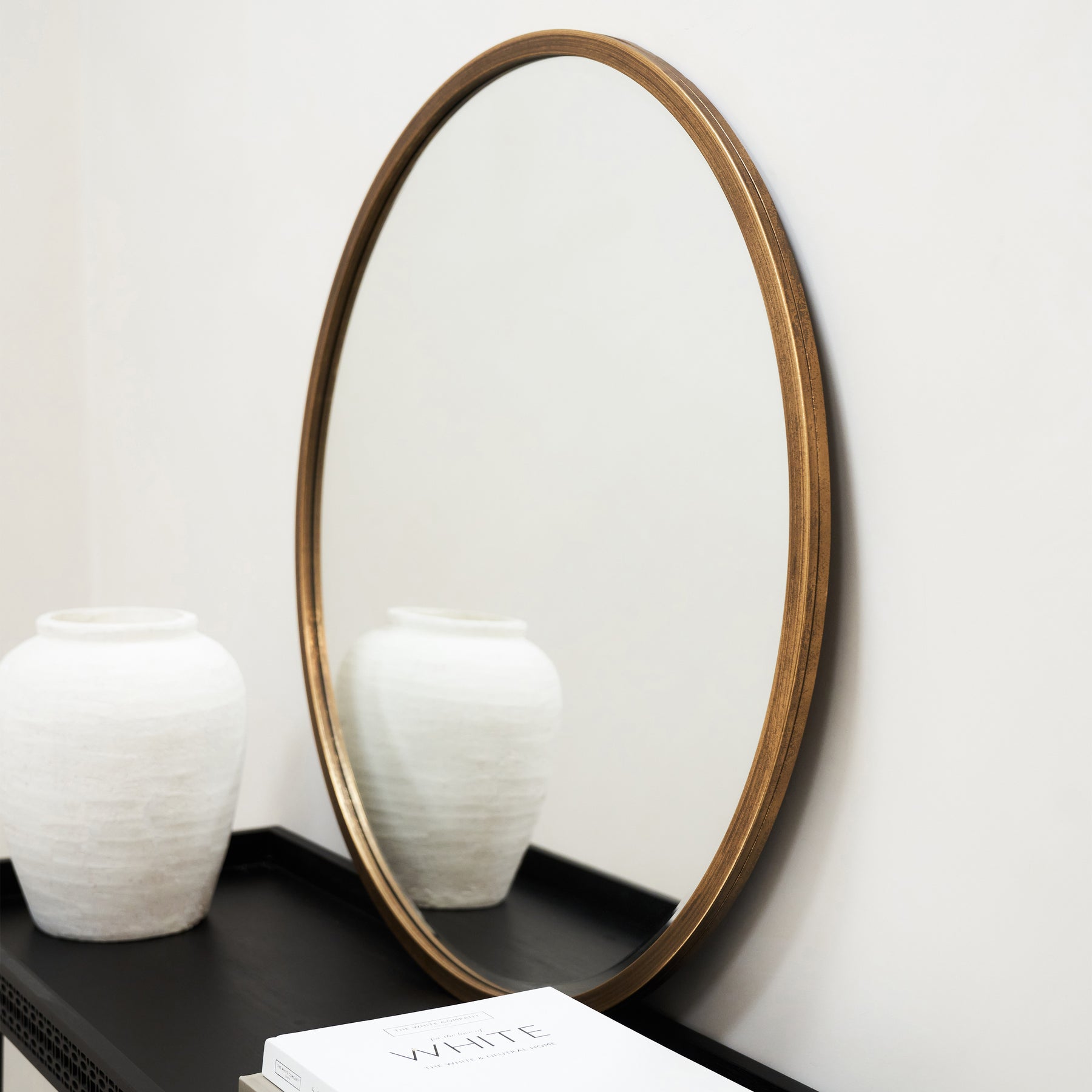 Gold Metal Modern Round Wall Mirror beside ceramic vase