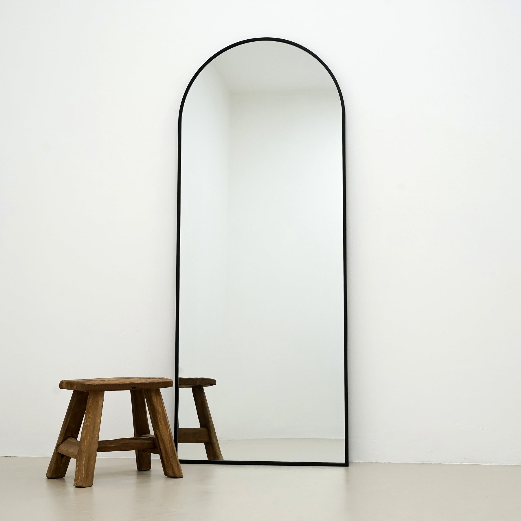 Champagne Full Length Arched Metal Mirror alternate shot beside wood stool