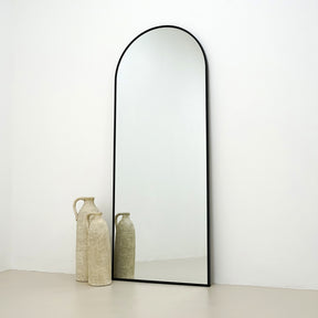 Champagne Full Length Arched Metal Mirror beside ceramic vases