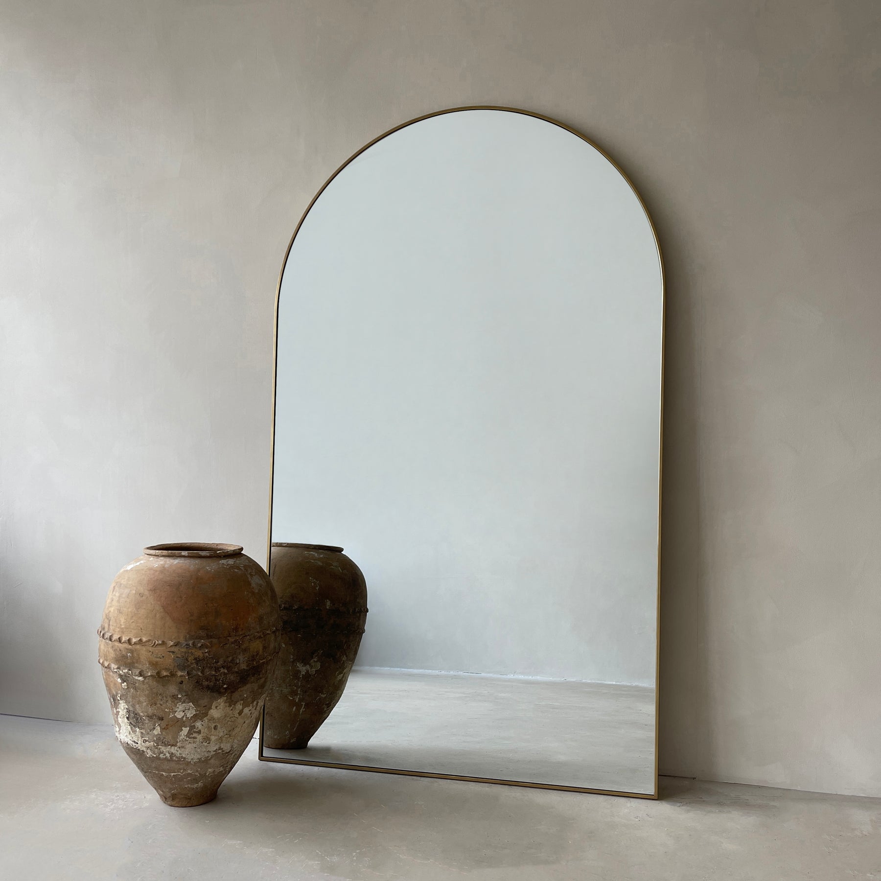 Gold Full Length Arched Metal Mirror beside ceramic vase