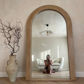 Full Length Arched Washed Wood Mirror beside ceramic vase