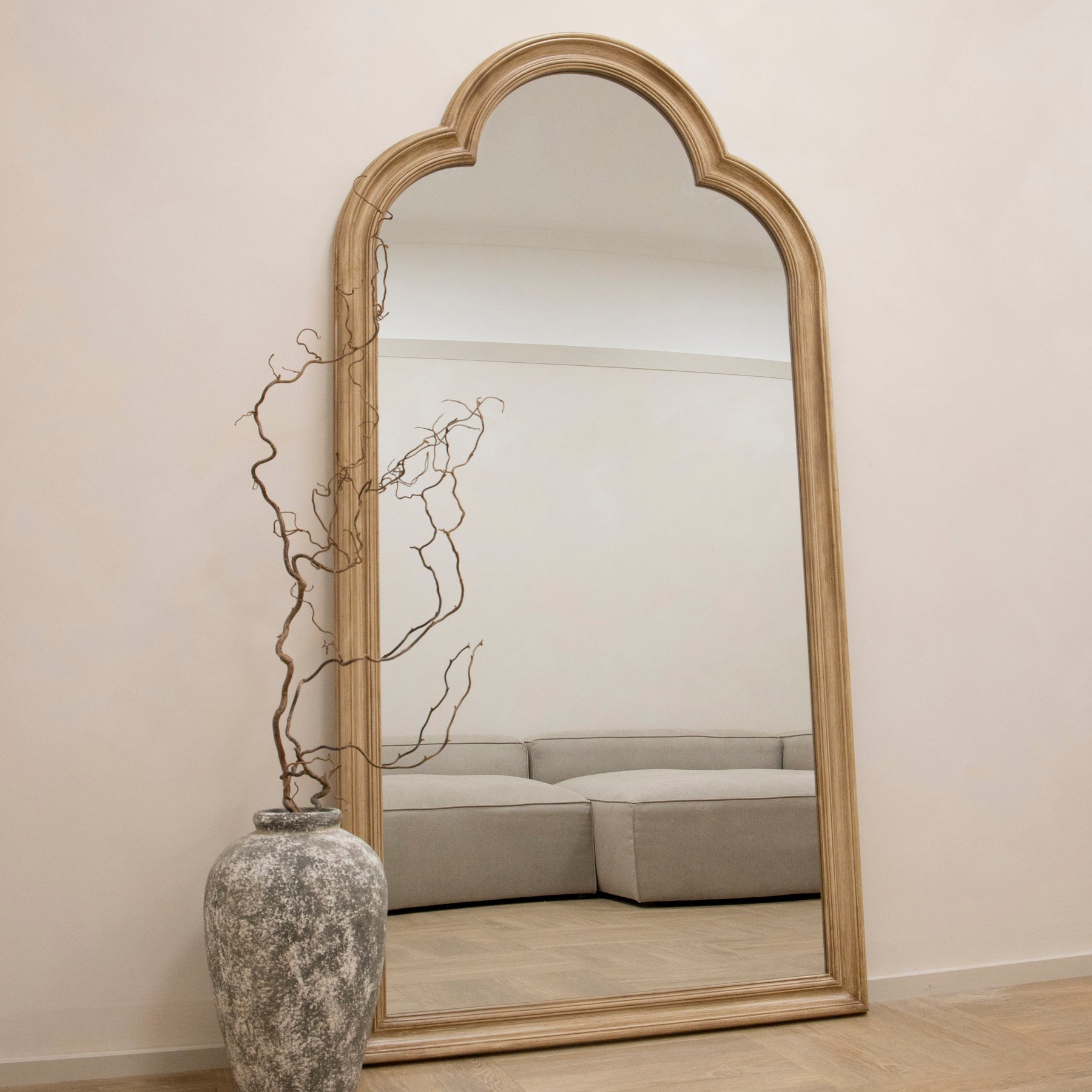 Washed Wood Arched Full Length Mirror reflecting sofa