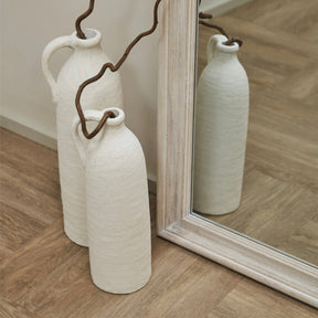 White Washed Wood Arched Full Length Mirror beside ceramic vases