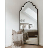 Black industrial arched metal full length mirror leaning against wall