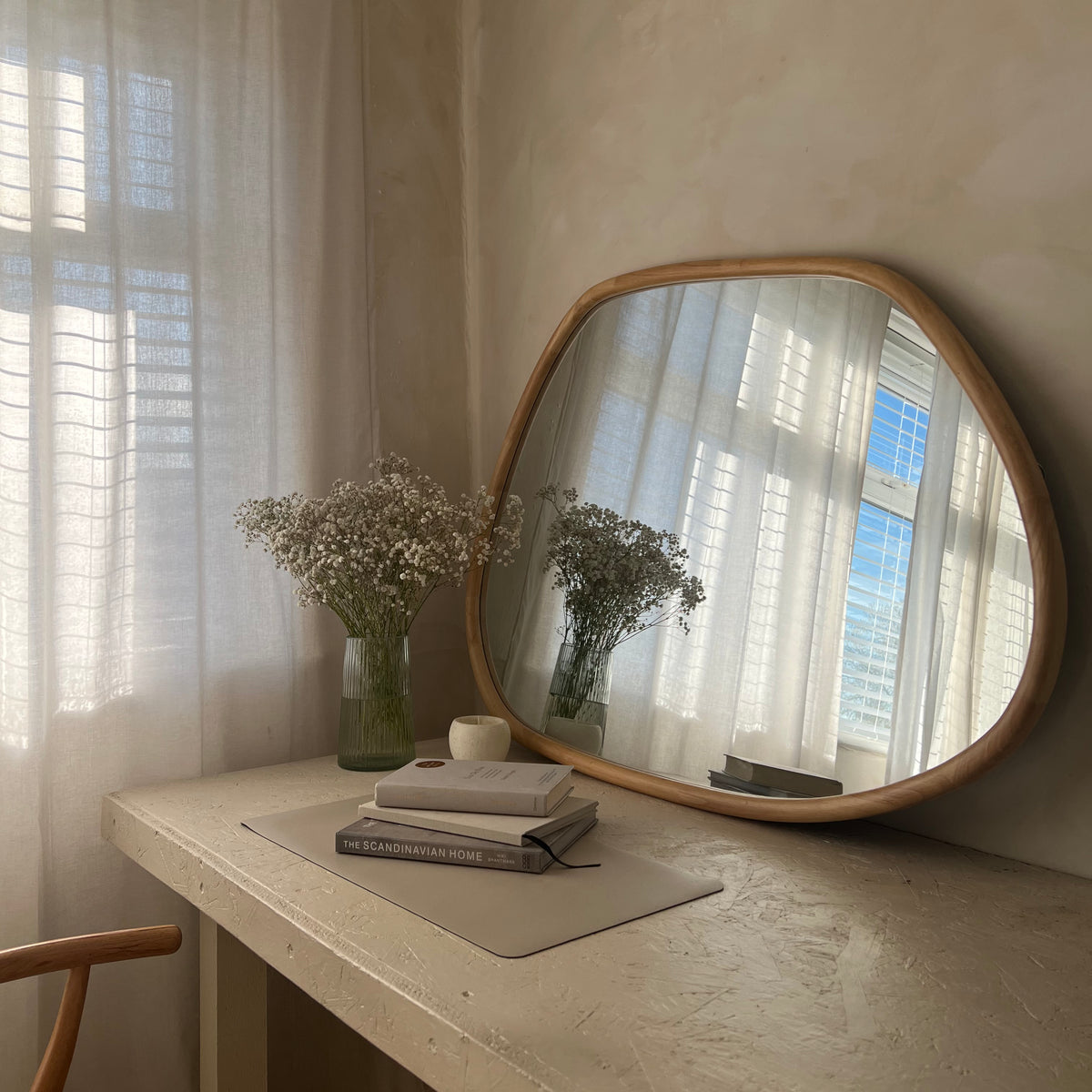 Organic irregular natural-coloured wooden mirror leaning against wall