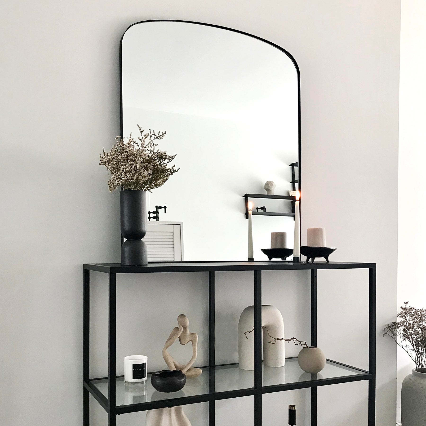 Black contemporary arched metal wall mirror displayed on console table