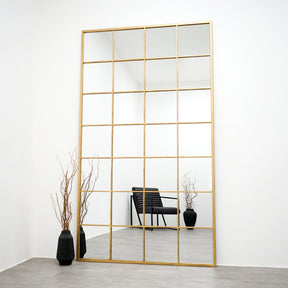 Full length extra large gold industrial metal window mirror leaning against wall
