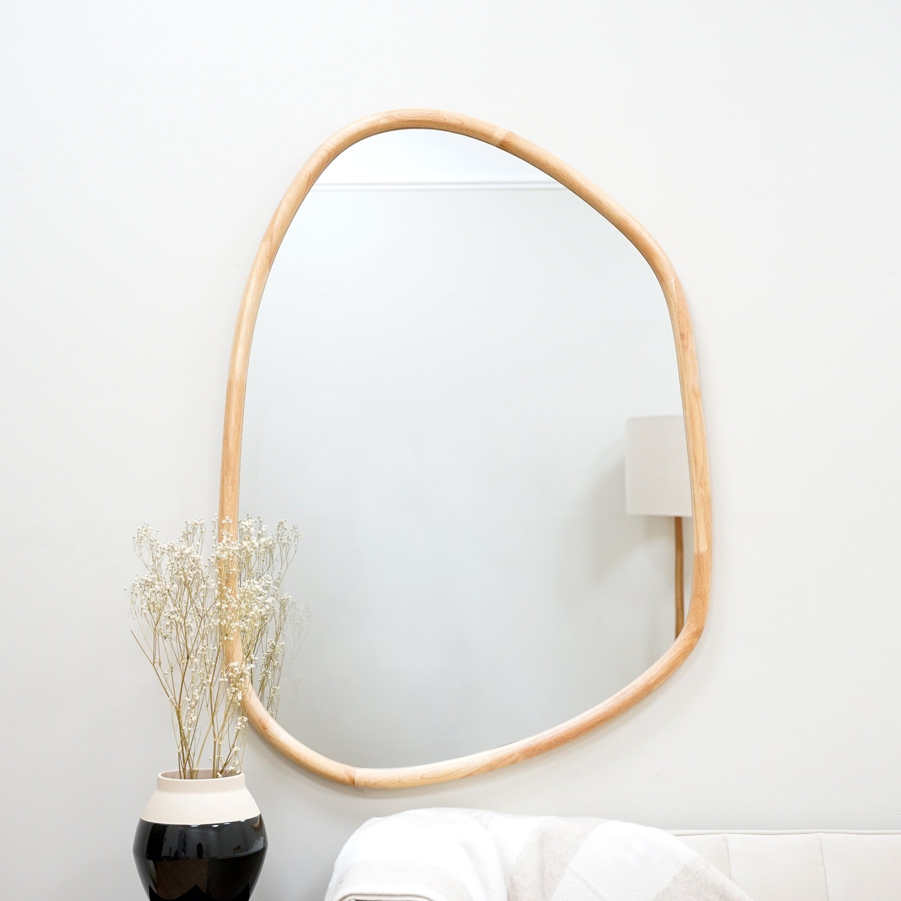 Organic irregular natural-coloured wooden wall mirror displayed vertically